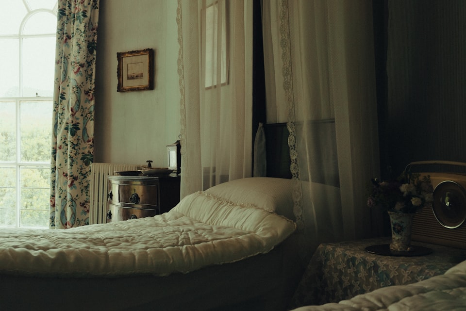 A cozy guest bedroom with a made bed beside a bright window